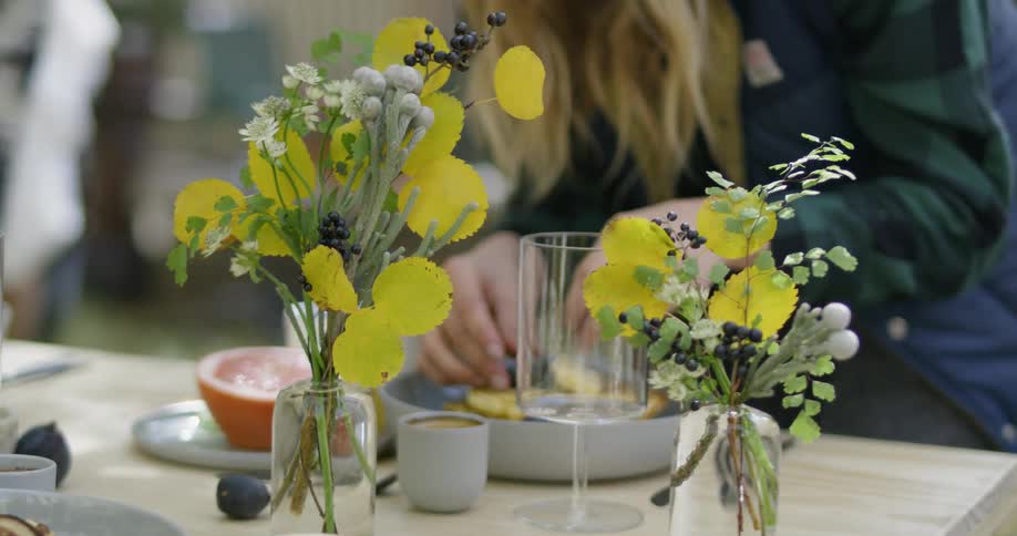 Woman is putting blueberries on pancakes on outside breakfast table