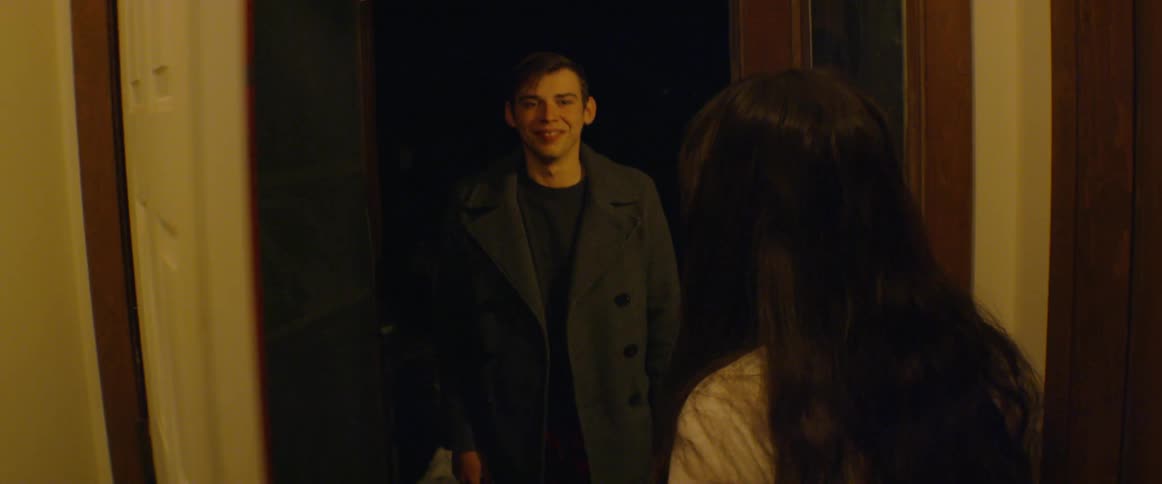 A man and woman hug and spin around in the doorway