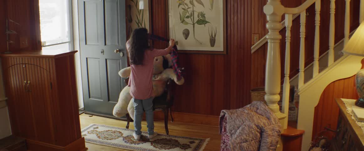 Child puts a scarf on a large teddy bear