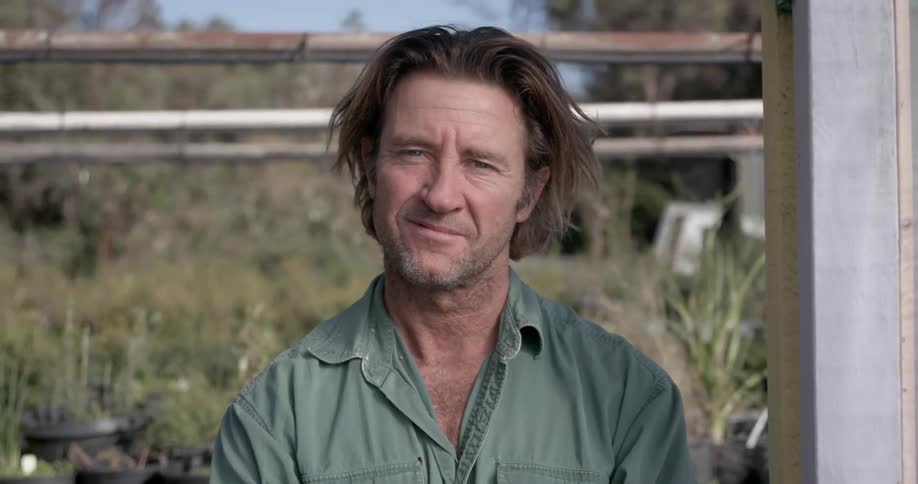 A man is smiling near his garden