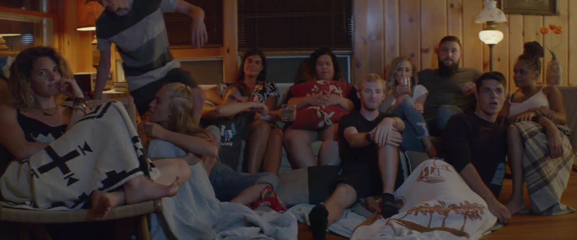 A group of people sit in a living room watching television