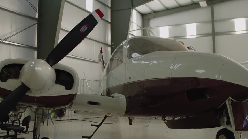 The plane is parked in the hangar on a sunny day