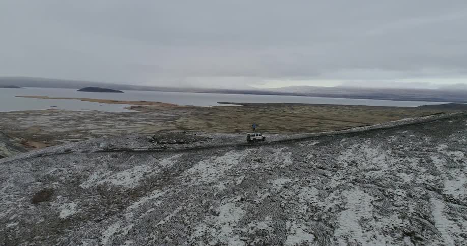 Person standing on top of a vehicle in a barren area on a cloudy day