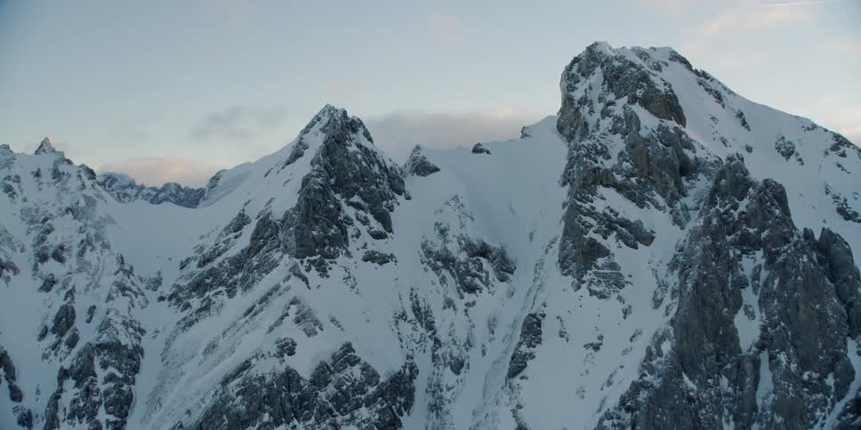 Clouds drift over snow covered mountains
