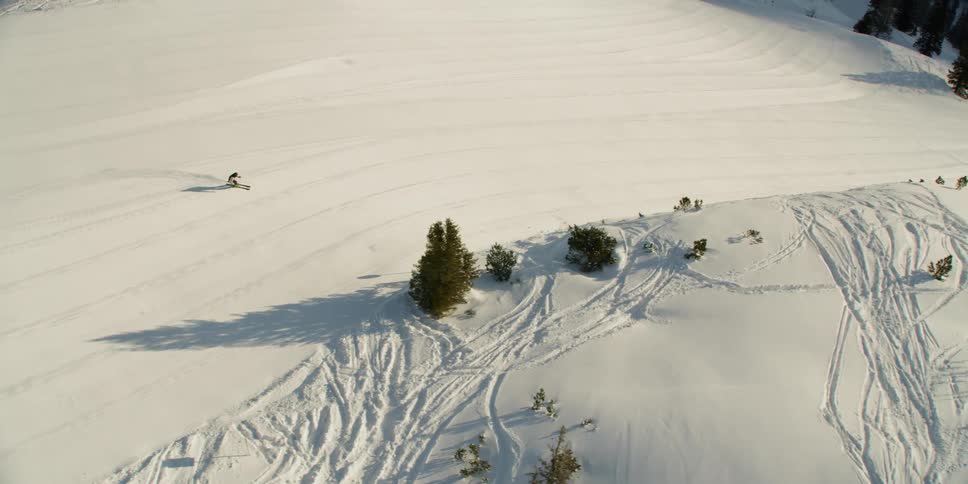 Man skiing down a wide slope of a mountain