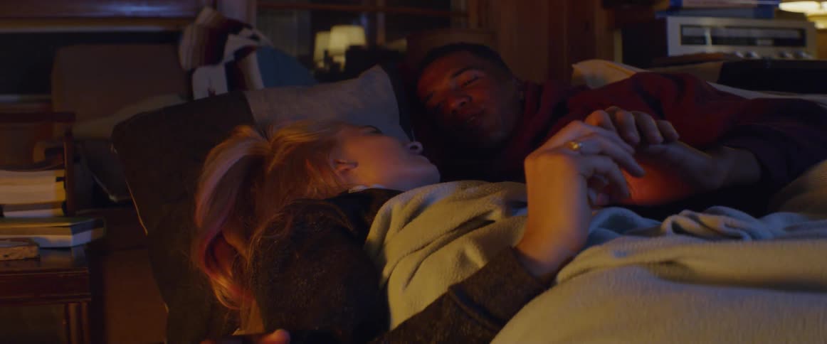A couple lay in bed together talking