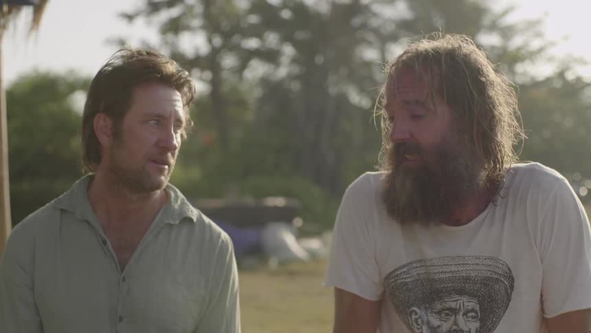 Two men talk outside on a sunny day