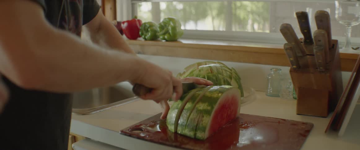 A man is cutting up a watermelon