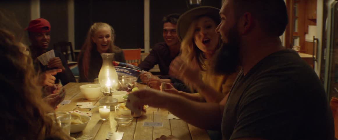 Men and women sitting at a table laughing and playing cards