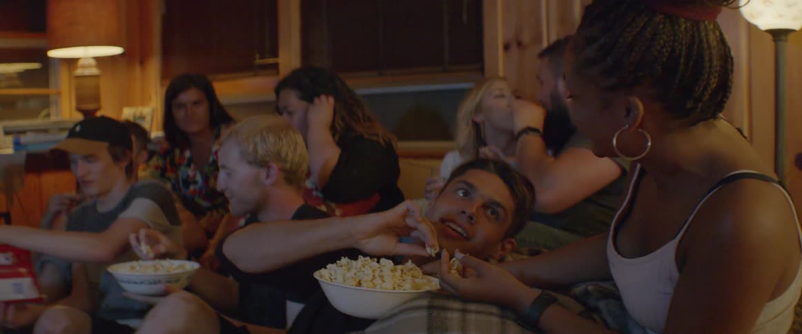 Friends share popcorn on a living room couch