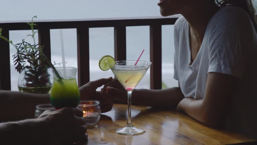 A couple hold hands at a table on their porch