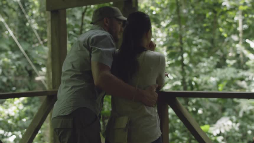 A man and woman look out into the forest