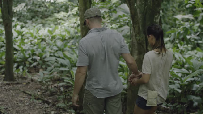 A man and woman hold hands while hiking in the forest