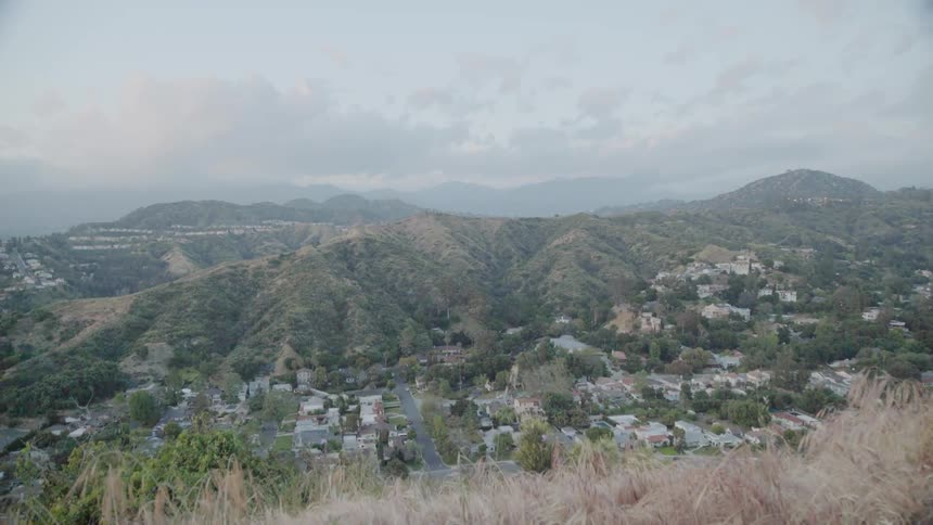 Clouds float above buildings and hills