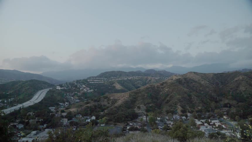 Clouds float above buildings and hills