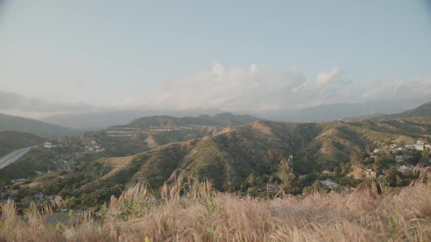 Clouds float above buildings and hills