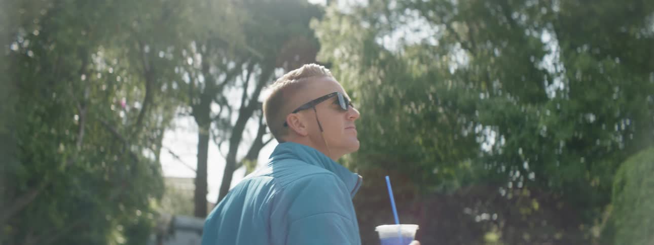 A man holds a plastic cup as he walks outside