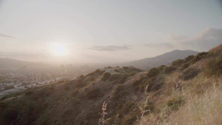 The sun sets over a city and surrounding hills