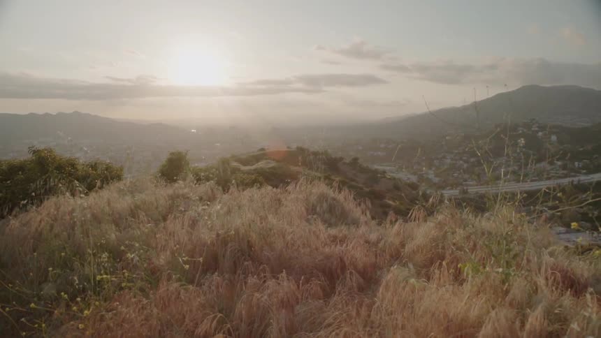The sun sets over a grassy hill