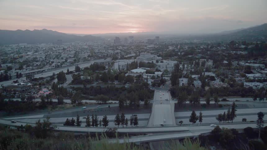 The highway by the city below has light traffic at sunset