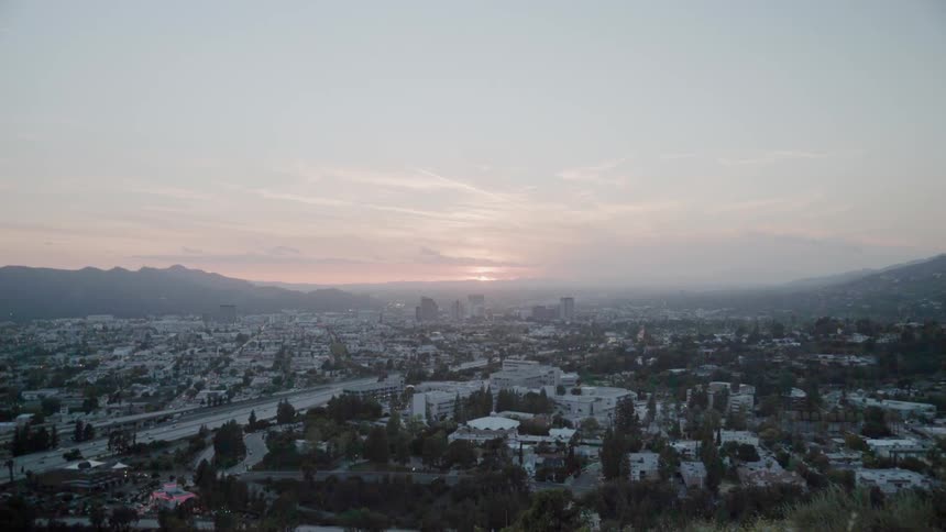 The sun is setting beyond a community in a valley