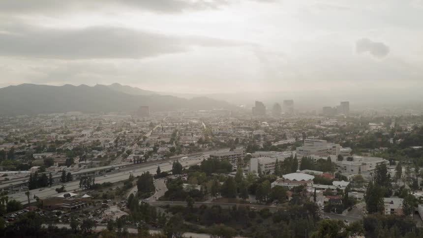 Clouds are hanging over a freeway in a sprawling community in daylight