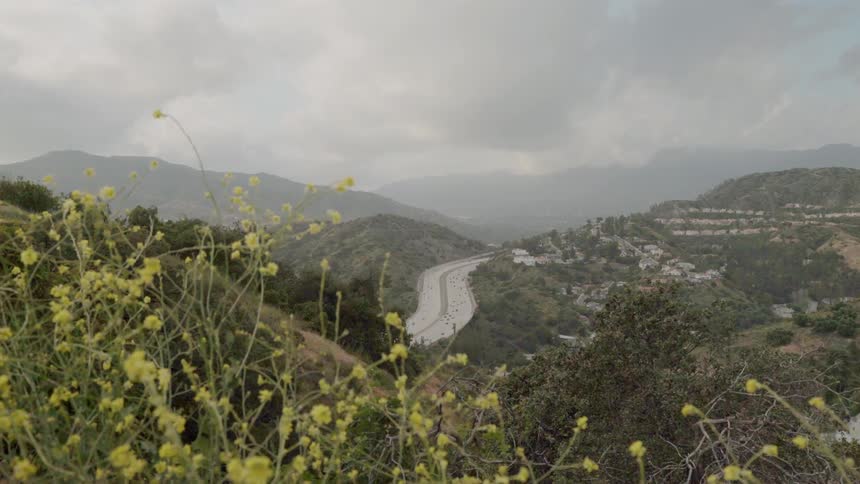 A freeway is flowing through a hilly community during a cloudy day