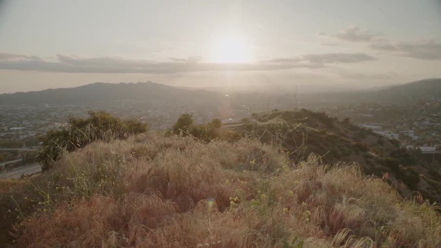 The sun sets over a grassy hill