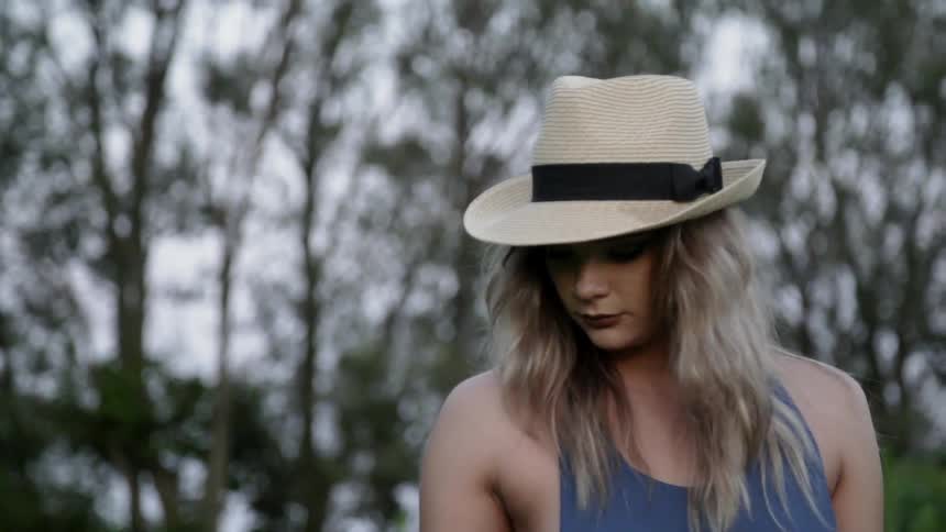 A woman is wearing a hat as she is walking outside during the day