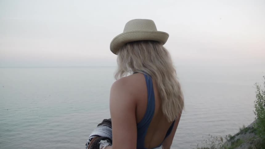 Woman wearing a hat looks out over a lake