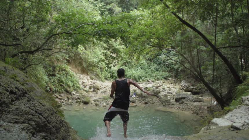 A man is jumping off a waterfall into water