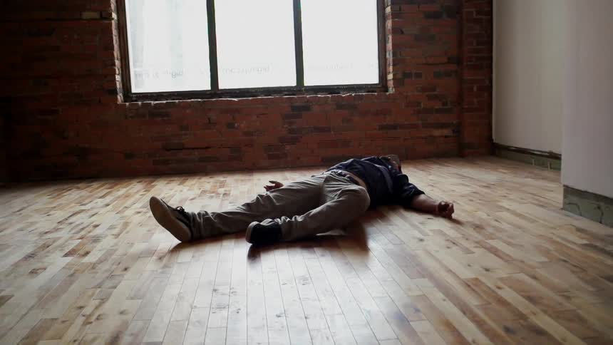 Person lying on a wood floor by a window