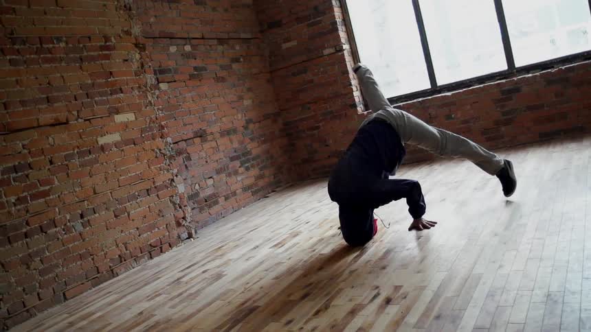 Man break dancing in an empty room with a window