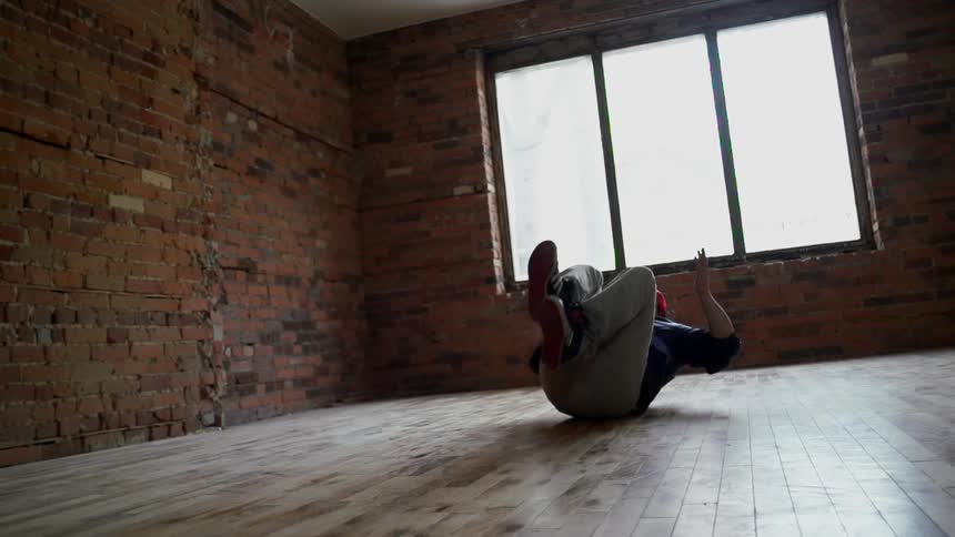A young man break dancing on a wooden floor