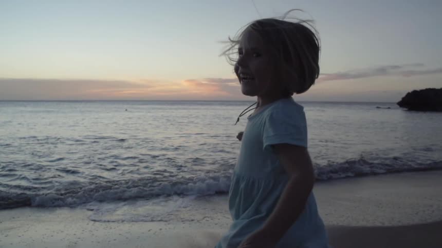 Child running on the beach at sunrise