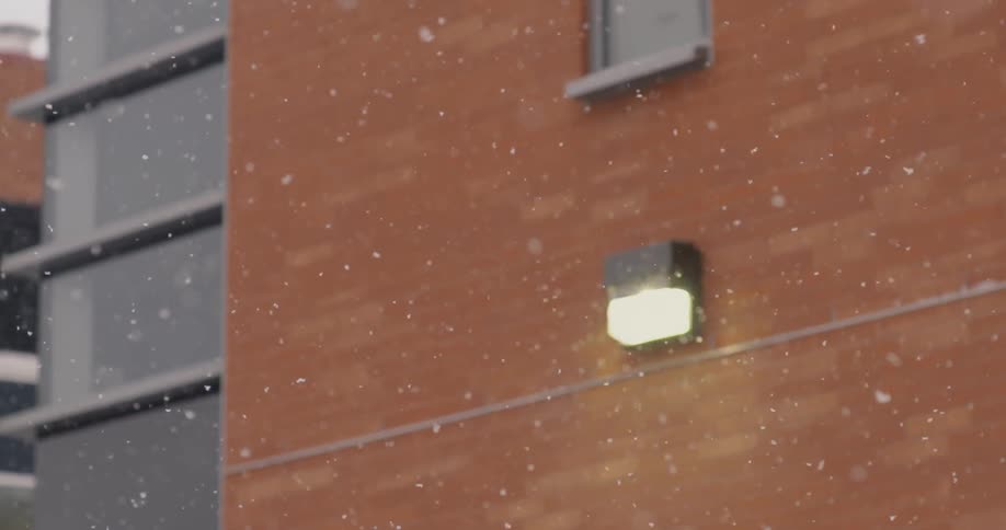 Snow falls slowly in front of a building