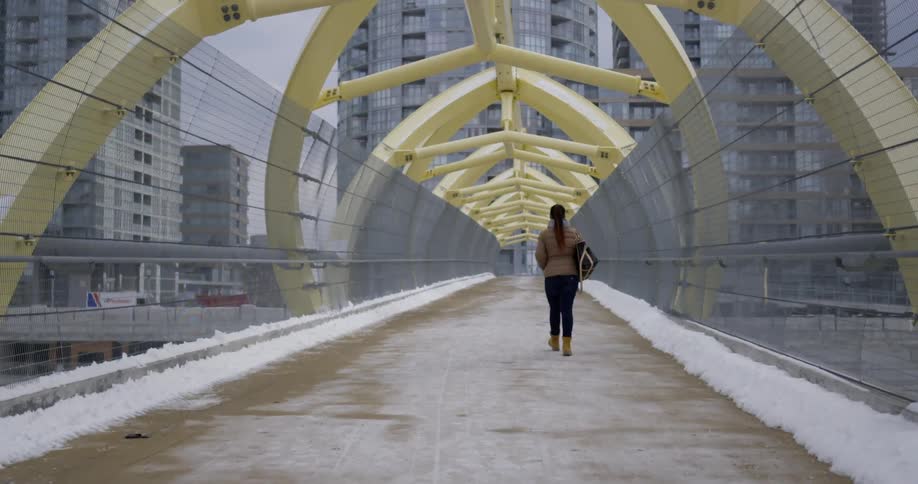 Woman walking on an overpass towards some buildings