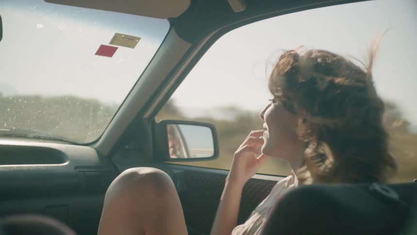 A woman rides in a car with the window down