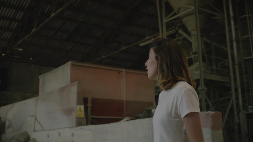 A woman in a warehouse turns and talks to someone