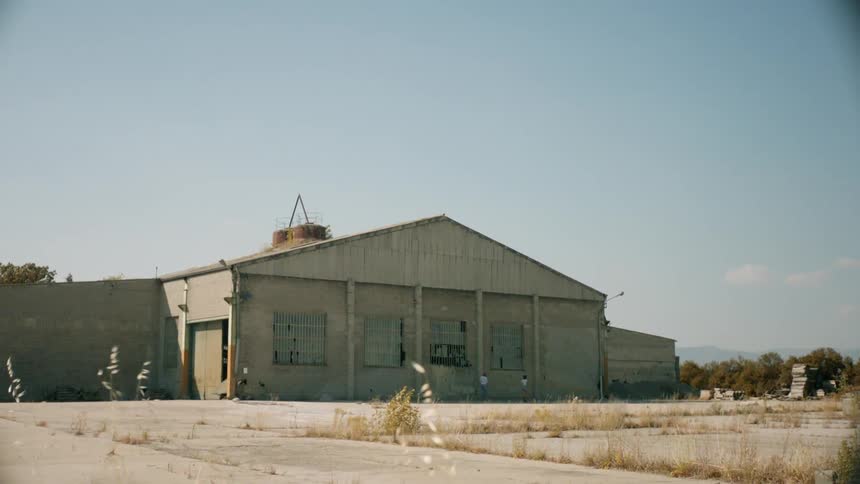 Two people walk around an abandoned building with broken windows