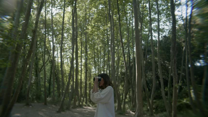 A woman takes a photo then continues down a tree lined trail