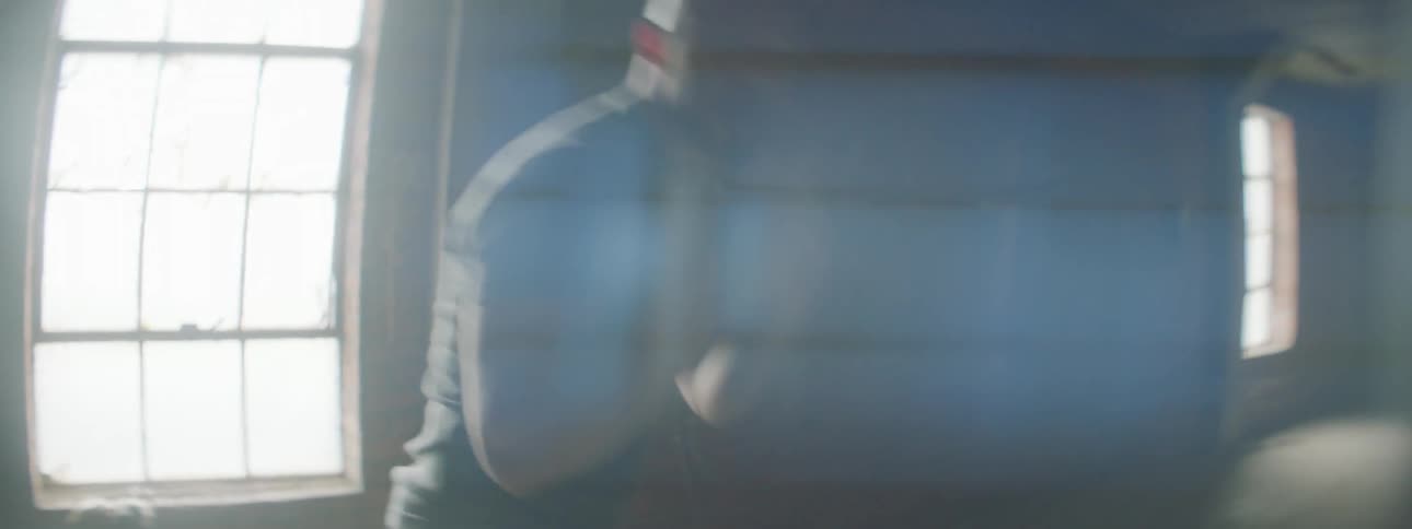 A man is shadow boxing inside a building during the day
