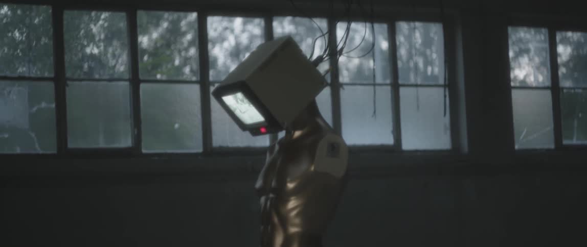 A mannequin has a television for a head in a warehouse