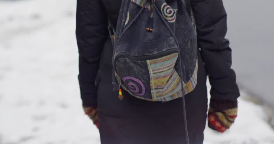 A girl walking on a snow covered sidewalk