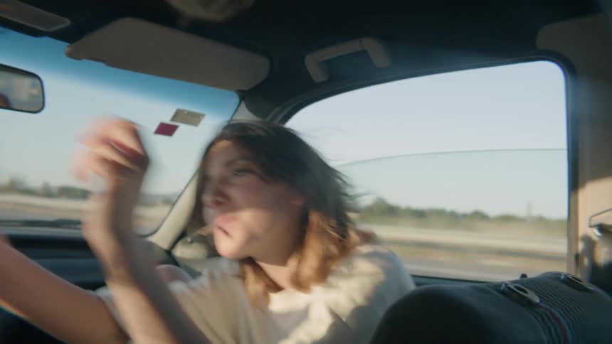The woman talks as she sits in the car