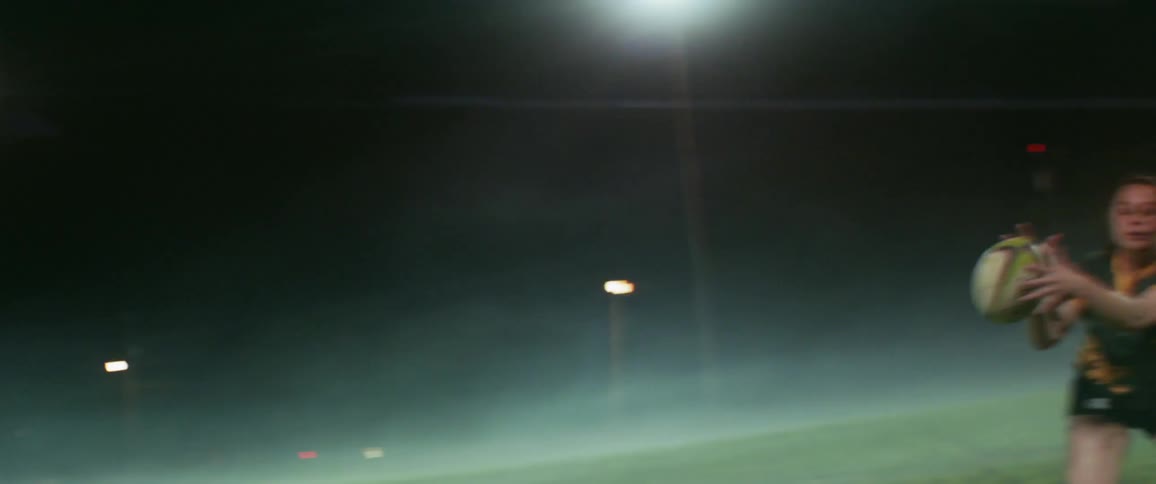 A women's rugby team is playing at night