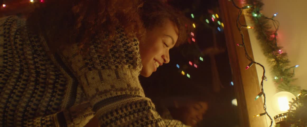 A woman in a sweater is decorating the christmas tree