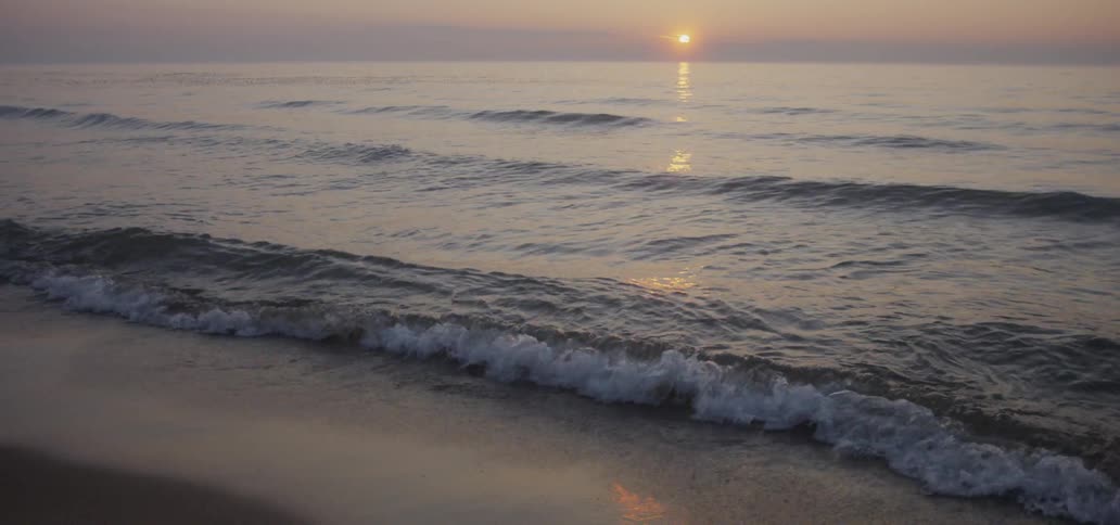 Ocean waves wash ashore at sunset