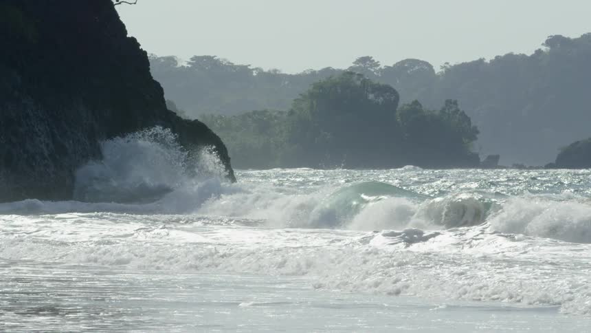 Waves crash into shore under a cloudy sky