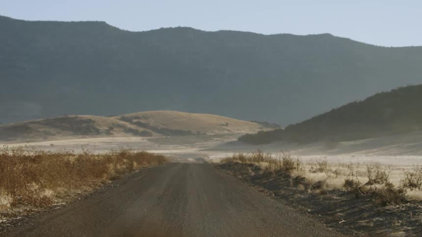 A vehicle travels on a rural dirt road